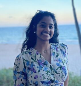Picture of Thulsi Prabakaran looking at the camera with a beach and the sea in the background